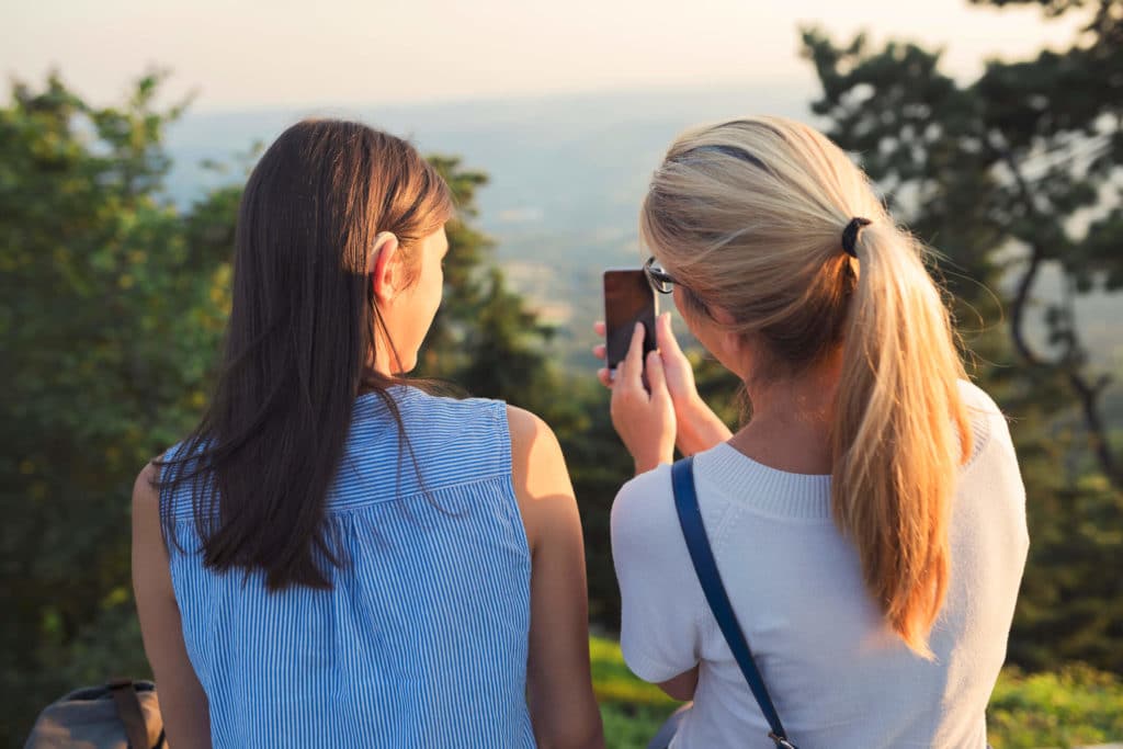 two San Luis Obispo local women looking at a scenic view with a phone