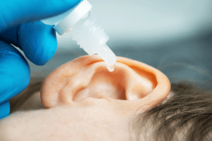 a horizontal ear with a dropper putting hydrogen peroxide drops into it
